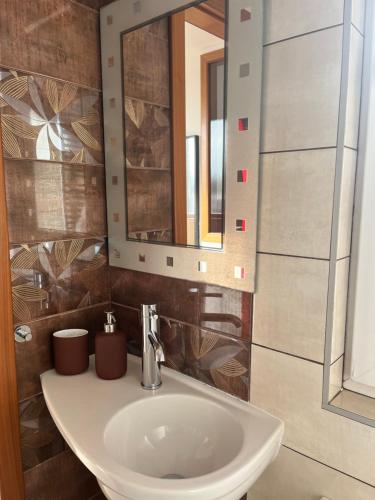 een badkamer met een witte wastafel en een spiegel bij Apartmán Simmy in Modřice