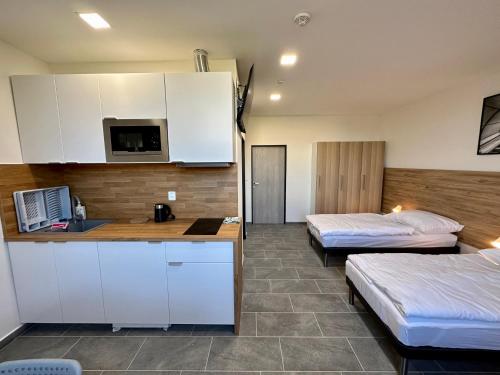 um quarto com duas camas e uma cozinha com armários brancos em Hotel Hangar em Mošnov