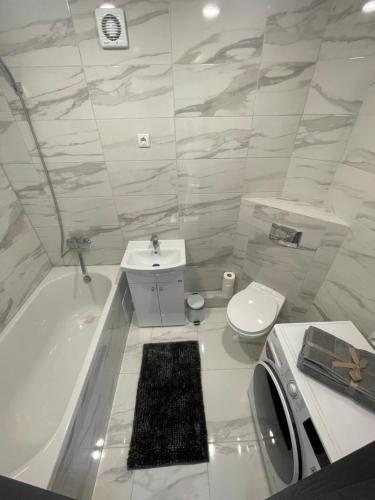 a bathroom with a tub and a toilet and a sink at Apartamentai in Marijampolė