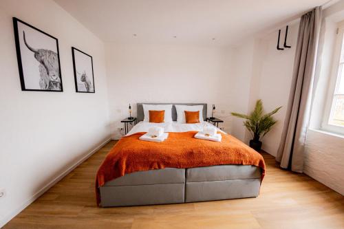 a bedroom with a large bed with orange blanket at Highlight am Stadtplatz Mühldorf - C4S COME4STAY - 2 Zimmer Wohnung I bis zu 5 Gäste in Mühldorf