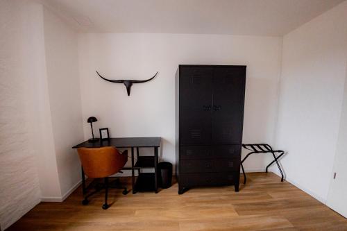 a room with a desk and a black cabinet and a chair at Highlight am Stadtplatz Mühldorf - C4S COME4STAY - 2 Zimmer Wohnung I bis zu 5 Gäste in Mühldorf