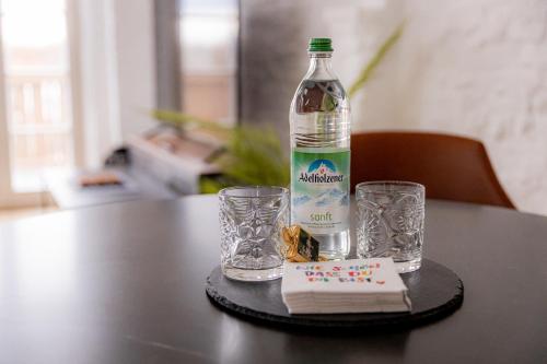 a bottle of water and two glasses on a table at Highlight am Stadtplatz Mühldorf - C4S COME4STAY - 2 Zimmer Wohnung I bis zu 5 Gäste in Mühldorf