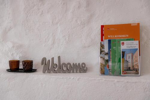 a shelf with a book and two cups on it at Highlight am Stadtplatz Mühldorf - C4S COME4STAY - 2 Zimmer Wohnung I bis zu 5 Gäste in Mühldorf
