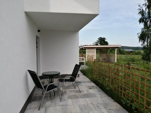 a patio with a table and chairs and a fence at Żabi Staw in Supraśl