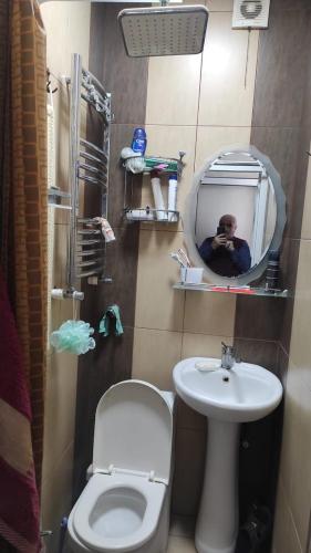 een man die een foto neemt van een badkamer met toilet en wastafel bij AYXAN HOSTEL in Ganja