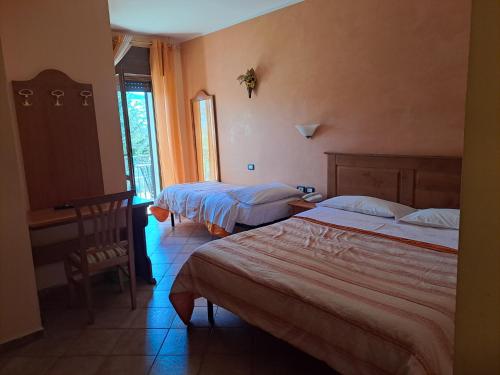 a bedroom with two beds and a desk and a window at Hotel LA LOGGIA in Castel di Sangro