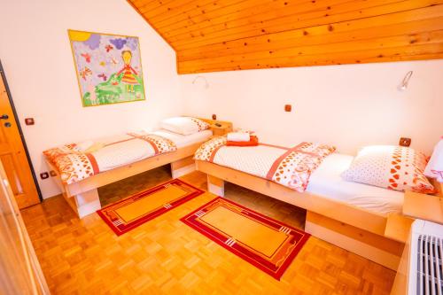 two twin beds in a room with wooden ceilings at Apartments Bohinj Mavrica in Bohinj