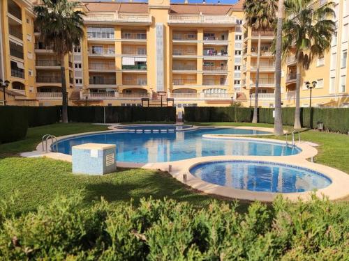 a swimming pool in front of a large building at Apartamento con piscina y vistas a la montaña in Denia
