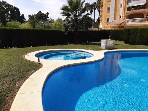 a large blue swimming pool in a yard at Apartamento con piscina y vistas a la montaña in Denia