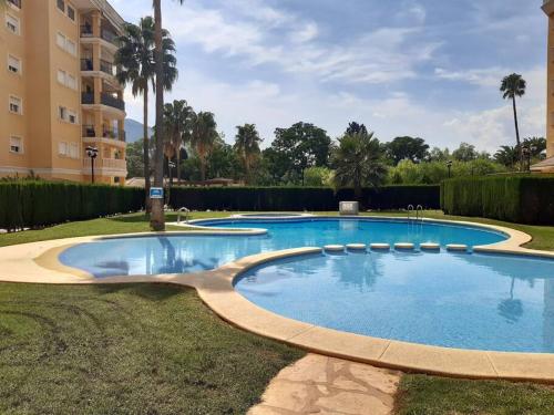 a large swimming pool in a yard next to a building at Apartamento con piscina y vistas a la montaña in Denia
