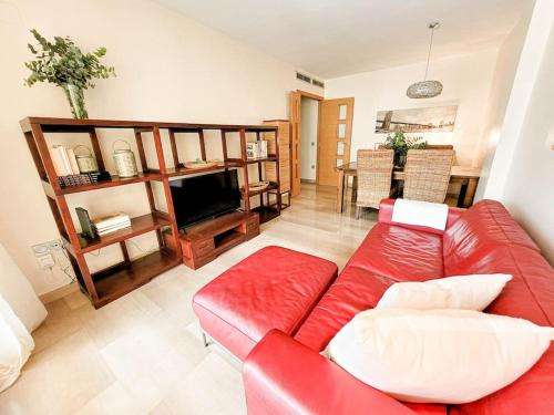a living room with a red couch and a television at Apartamento con piscina y vistas a la montaña in Denia