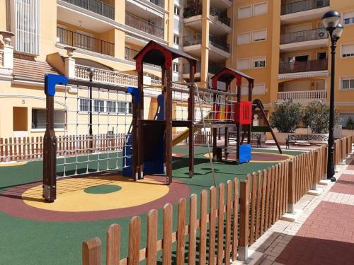 a playground in front of a apartment building at Apartamento con piscina y vistas a la montaña in Denia