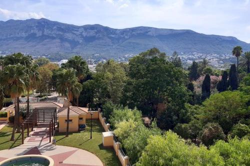 a view of a house with mountains in the background at Apartamento con piscina y vistas a la montaña in Denia