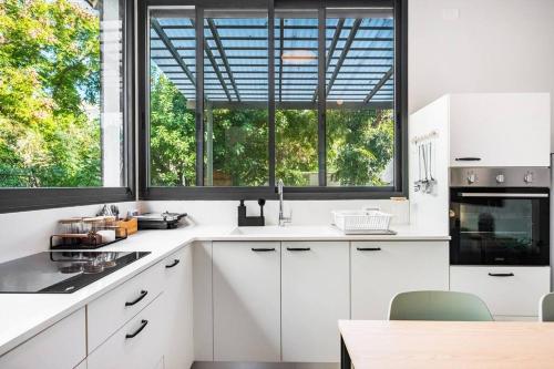 a kitchen with white cabinets and a large window at Sweet and rural home in Ra’anana in Ra‘ananna