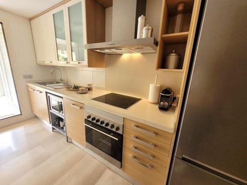 a kitchen with a stove and a refrigerator at Apartamento con piscina y vistas a la montaña in Denia