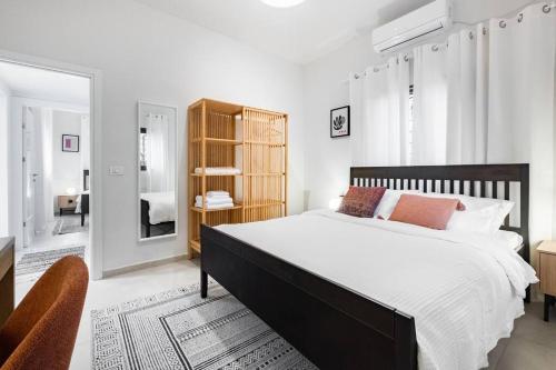a white bedroom with a large bed and a mirror at Sweet and rural home in Ra’anana in Ra‘ananna