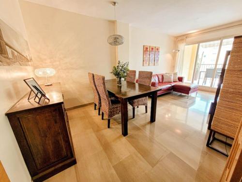a living room with a table and chairs and a couch at Apartamento con piscina y vistas a la montaña in Denia