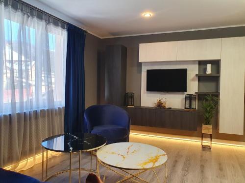 uma sala de estar com uma cadeira azul e uma televisão em Irish House em Sinaia