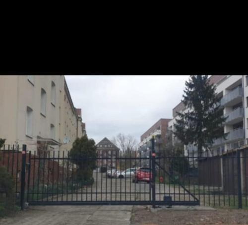 una cerca negra con un coche rojo detrás de ella en King Piastów & SPA, en Szczecin
