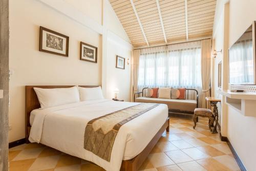 a hotel room with a bed and a couch at Chuchaiburi Sri Amphawa in Amphawa