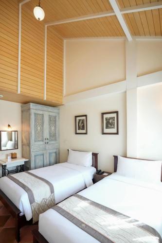 two beds in a room with wooden ceilings at Chuchaiburi Sri Amphawa in Amphawa