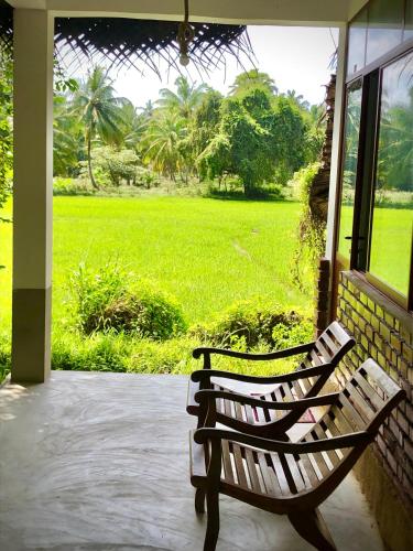 a bench sitting on a porch looking out at a field at Wilpattu Green Cabin in Achchamulai