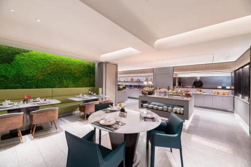 a restaurant with tables and chairs and a green wall at Intercity Yangzhou Slender West Lake in Yangzhou