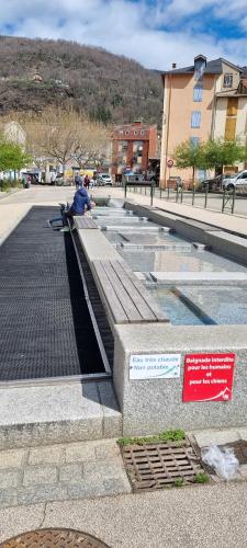 a person sitting on a bench next to a fountain at AX proche départ rando - piscine - parking gratuit in Ax-les-Thermes