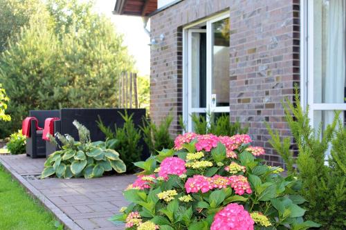 a garden with pink and yellow flowers in front of a house at Lesny Apartament in Ostrzyce