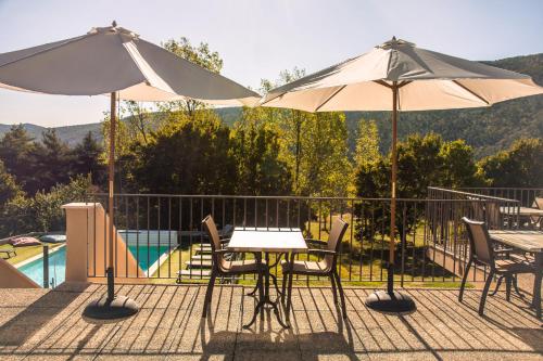 a table and chairs with umbrellas on a patio at Hôtel le Panoramic - Votre Hôtel au cœur des Gorges du Verdon in La Palud sur Verdon