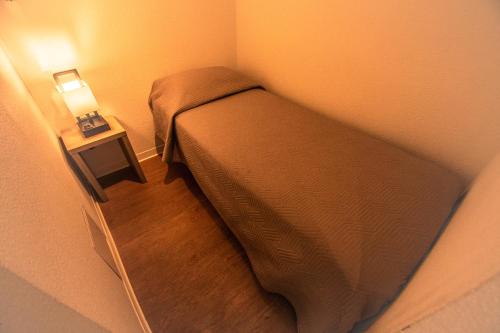 a small bedroom with a bed and a night stand at Hôtel le Panoramic - Votre Hôtel au cœur des Gorges du Verdon in La Palud sur Verdon