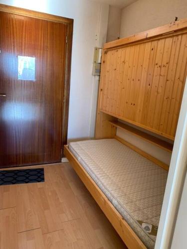 Cette petite chambre comprend un lit et une porte en bois. dans l'établissement Chamrousse le Vernon, à Chamrousse
