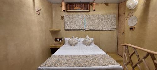 a small bedroom with a bed with white sheets and pillows at Matsya in Havelock Island