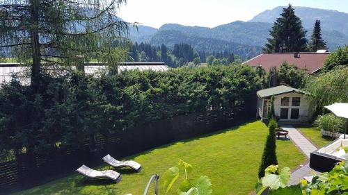 a garden with a stone wall and a lawn with chairs at Gästehaus Tanneck in Reit im Winkl