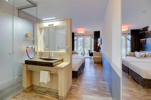 a bathroom with a sink and a mirror and two beds at Hotel Erve Hulsbeek in Oldenzaal