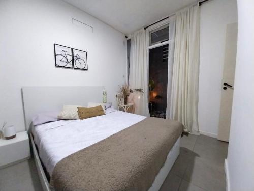 サンタフェにあるDpto Maipuの大きなベッドと窓のある白い寝室