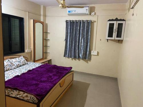 浦那的住宿－Spacious 2 BHK near Commerce Zone，一间卧室配有一张带紫色毯子的床