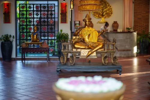 a statue of a man sitting on a bench in a room at SAKABAN Suite in Siem Reap