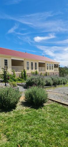 ein großes gelbes Gebäude mit Büschen davor in der Unterkunft Canyonleigh Retreat in Canyonleigh