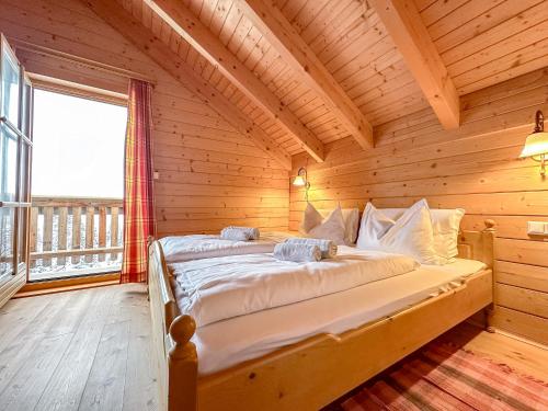 a bed in a wooden room with a large window at 1A Chalet Koralpenzauber - Wandern, Grillen, Sauna und Traumblick in Wolfsberg
