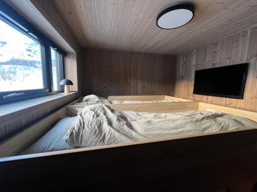 um quarto com uma cama e uma televisão de ecrã plano em Moderne hytte på Fjellsætra, Ski in/Out, Familievennlig em Sykkylven