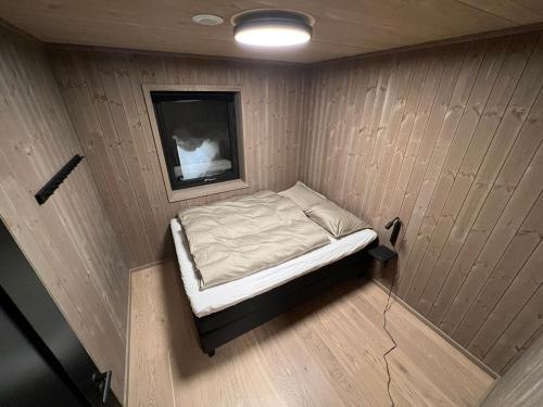 uma pequena cama num pequeno quarto com uma televisão em Moderne hytte på Fjellsætra, Ski in/Out, Familievennlig em Sykkylven