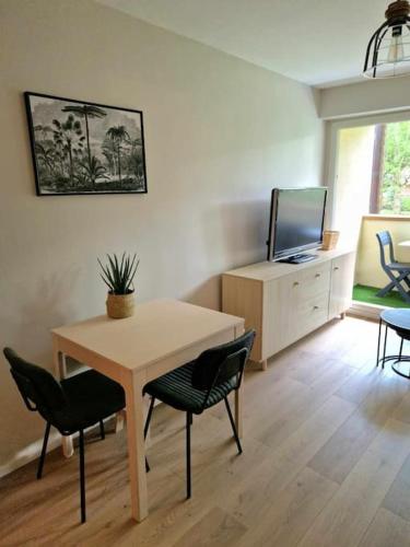 un salon avec une table, des chaises et une télévision dans l'établissement Joli appartement avec balcon, à Cabourg