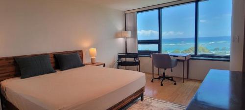 a bedroom with a bed and a desk with a view of the ocean at Moana Luxury Residence in Honolulu