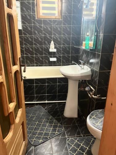 a black tiled bathroom with a sink and a toilet at Apartament Cornelia in Buzău