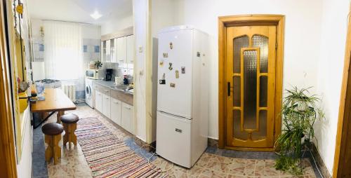 a kitchen with a white refrigerator and a wooden door at Apartament Cornelia in Buzău