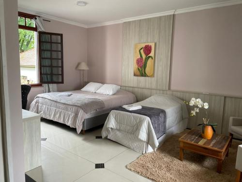 1 dormitorio con 2 camas y mesa. en Hotel Villa Souza Ltda en Santa Cruz do Sul