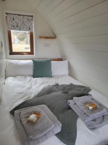 un letto con asciugamani sopra in una piccola stanza di Handa pod in scottish highlands. a Scourie