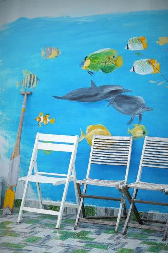 two chairs in front of a mural of whales and dolphins at Sông Suối Homestay in Quy Nhon