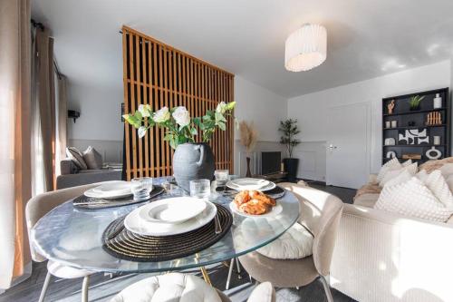 - un salon doté d'une table en verre avec des assiettes et des fleurs dans l'établissement CineHome - 5 min Tours centre-Parking/Tram au pied, à Tours